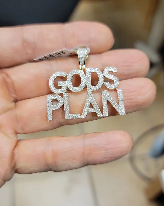 Iced-out block letter word pendant held between fingers