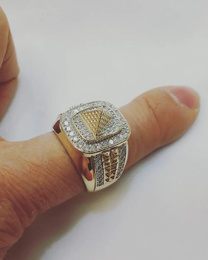Iced gold signet ring with a pyramid center worn on a thumb