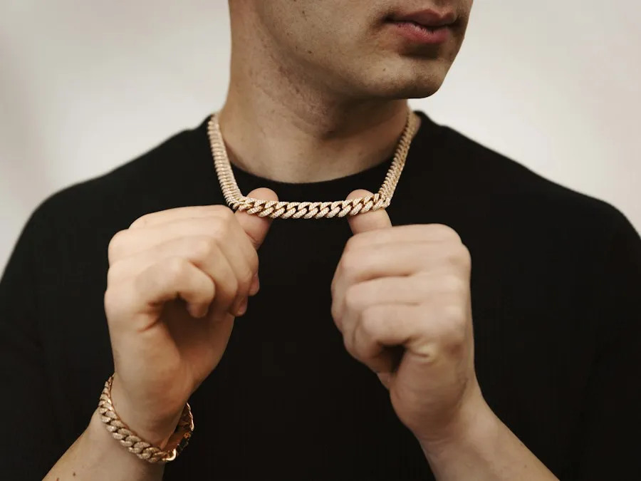 Man holding a rose gold Cuban chain with a matching bracelet