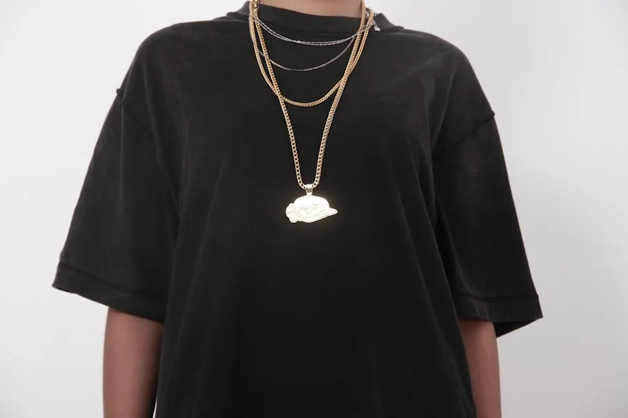 Layered gold chains with a pendant over a black tee