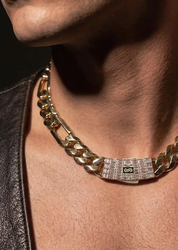 Gold Figaro chain with an iced baguette clasp worn at the collarbone