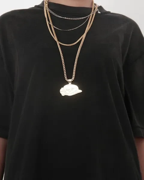 Man in a black tee wearing gold and silver chains layered at different lengths with a pendant