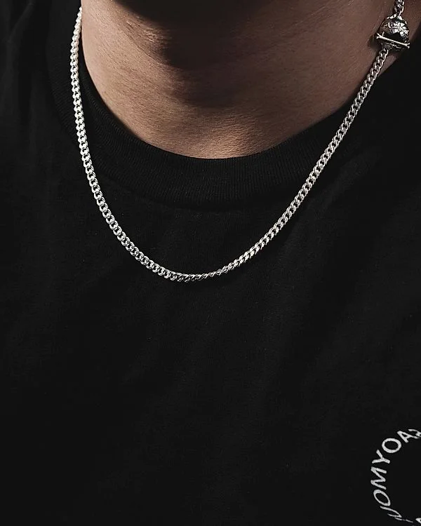 Single silver Cuban chain over a black tee