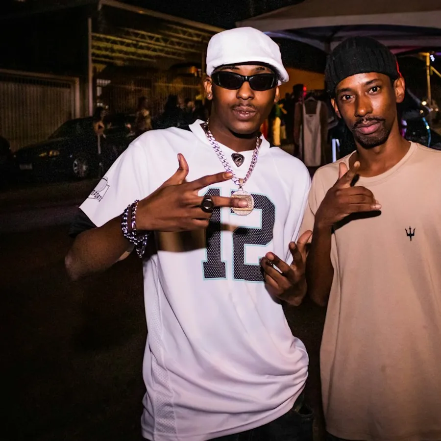 Two friends at a night event wearing chains and caps
