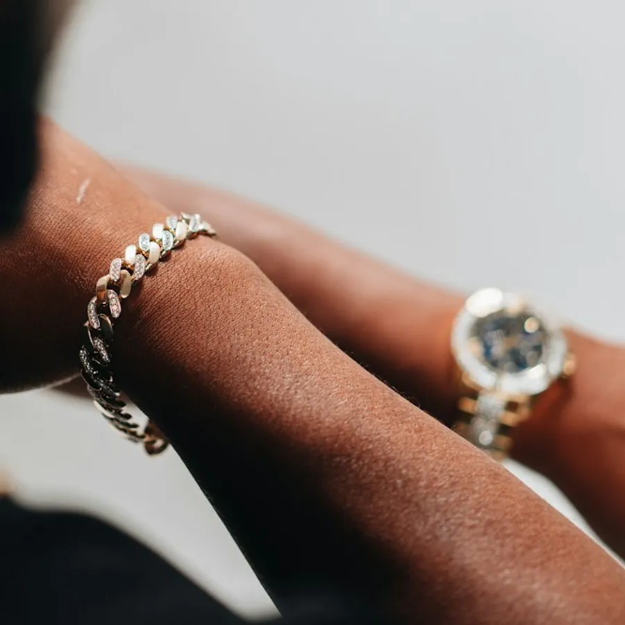 Close-up of a gold link bracelet and watch on a wrist