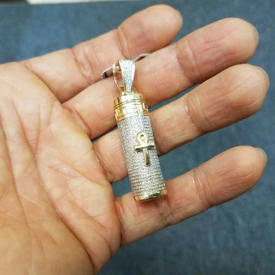Iced-out gold ankh cylinder pendant held in a palm