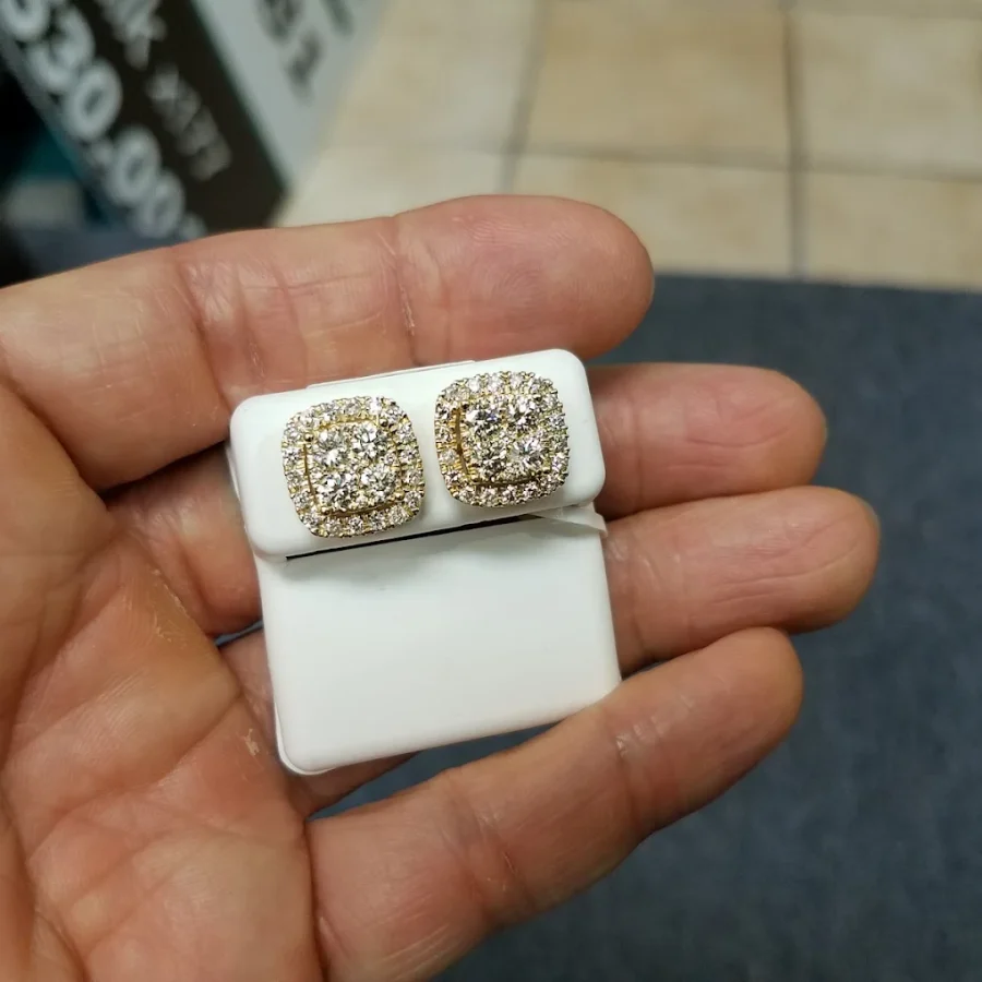 Iced cushion halo stud earrings on a card held in a palm