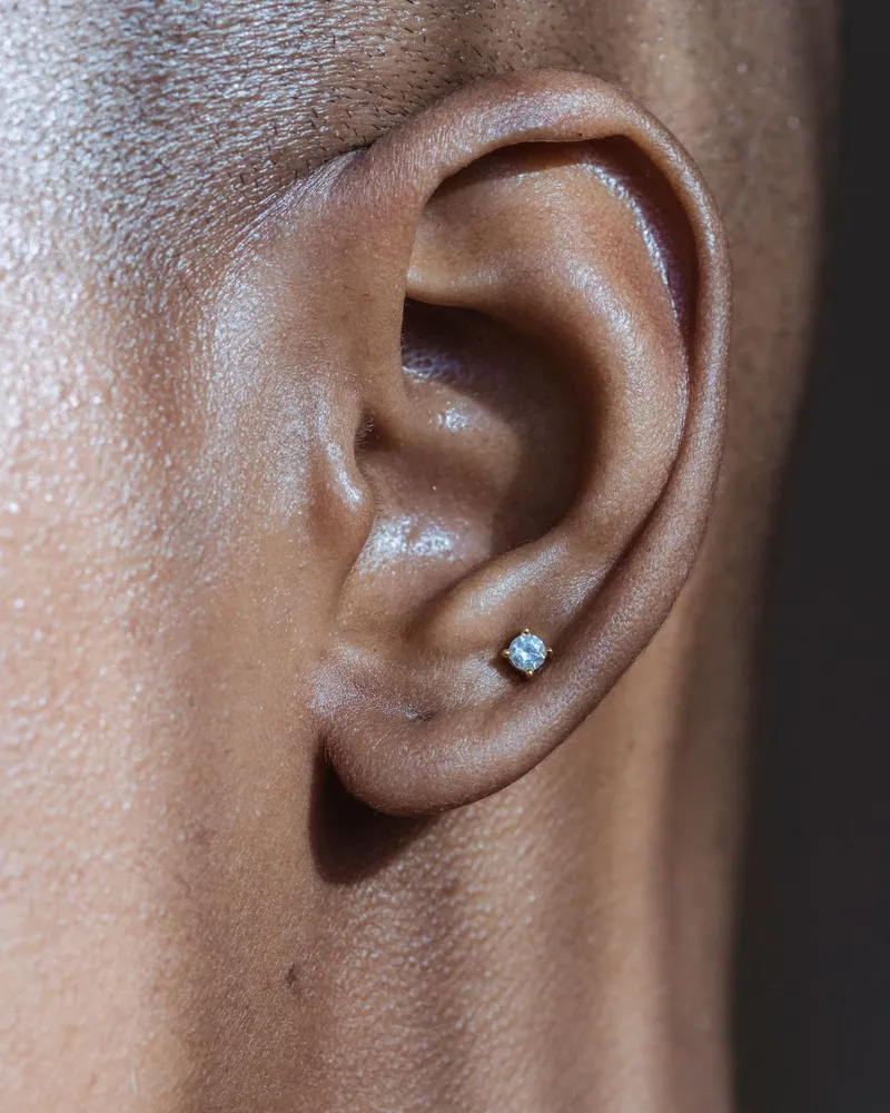 Small diamond stud earring on an ear, seen up close