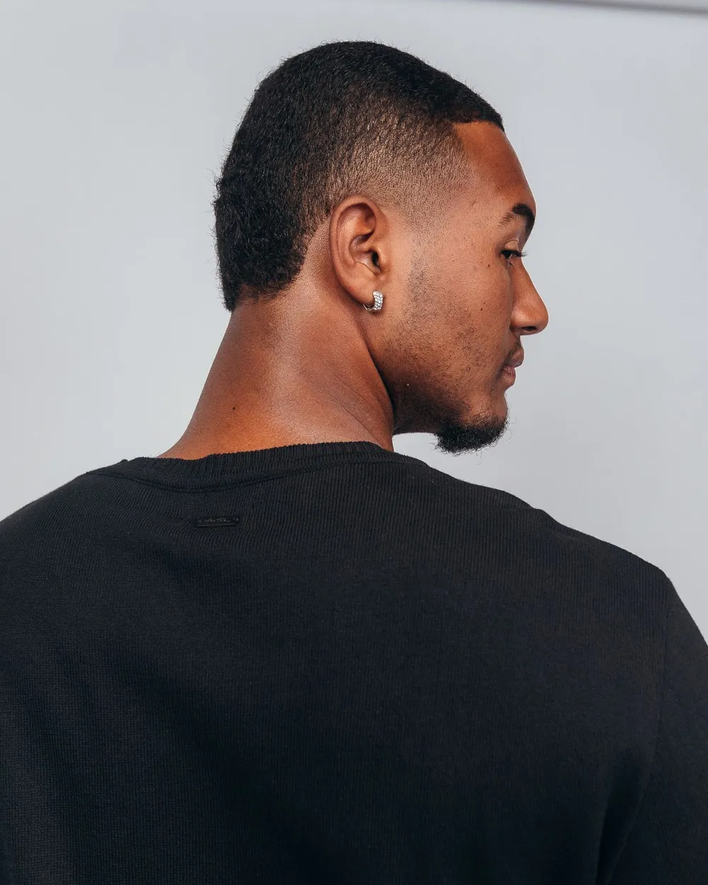 Man in a black sweater wearing a small diamond stud