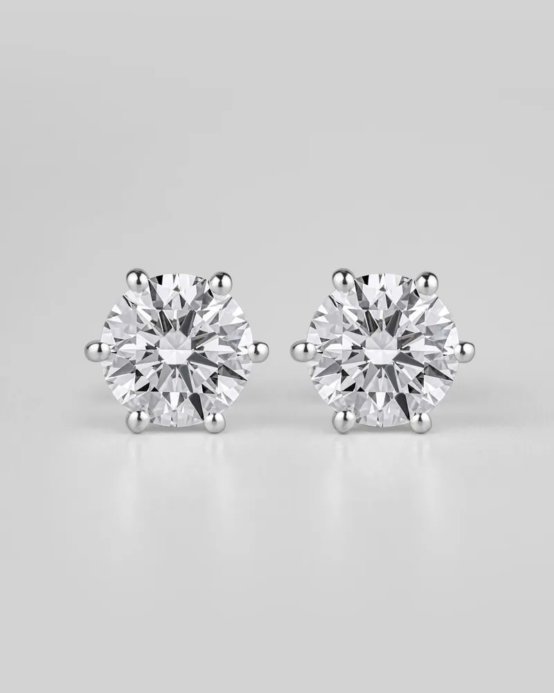 Pair of round six-prong diamond studs on a white background